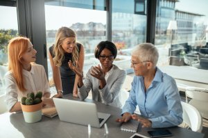 Smiling business women working on the laptop together.