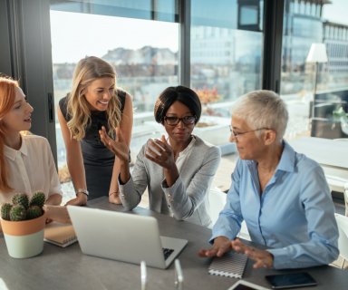 Smiling business women working on the laptop together.