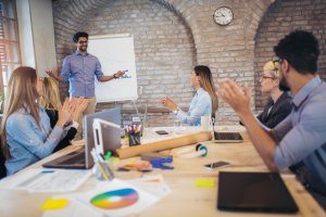 Businessman At Whiteboard Giving Presentation In Boardroom