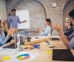 Businessman At Whiteboard Giving Presentation In Boardroom