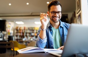 Smiling male student working and studying in a library