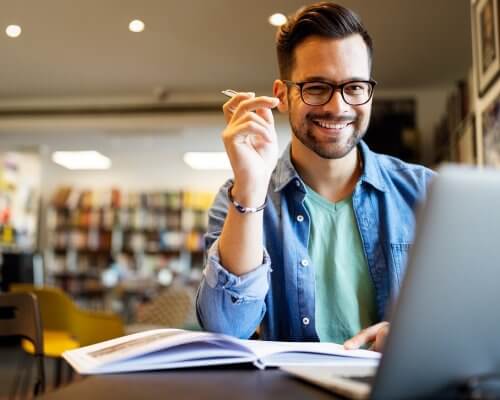 Smiling male student working and studying in a library