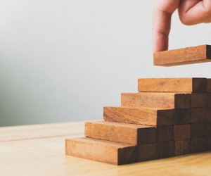 Hand arranging wood block stacking as step stair. Ladder career path concept for business growth success process